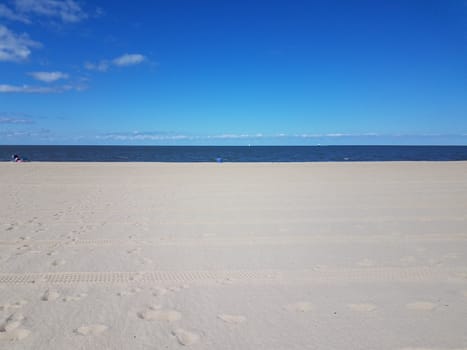 tire tracks and foot prints on sand on combed beach and sea water