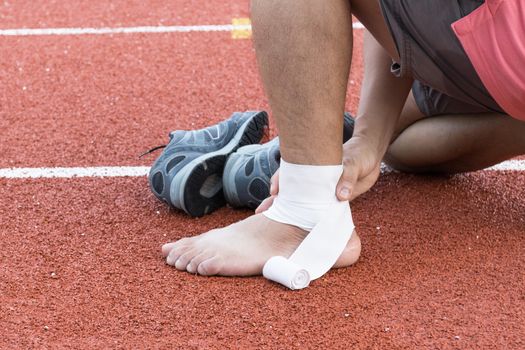 man applying compression bandage onto ankle injury After exercise concept Sports injuries.
