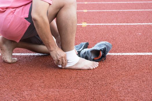 man applying compression bandage onto ankle injury After exercise concept Sports injuries.
