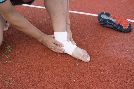 man applying compression bandage onto ankle injury After exercise concept Sports injuries.
