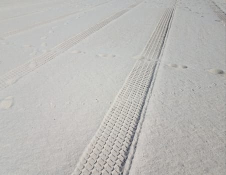 tire tracks and foot prints on sand on combed beach