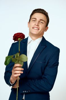 A man in a suit with a rose in his hands a gift date light background. High quality photo