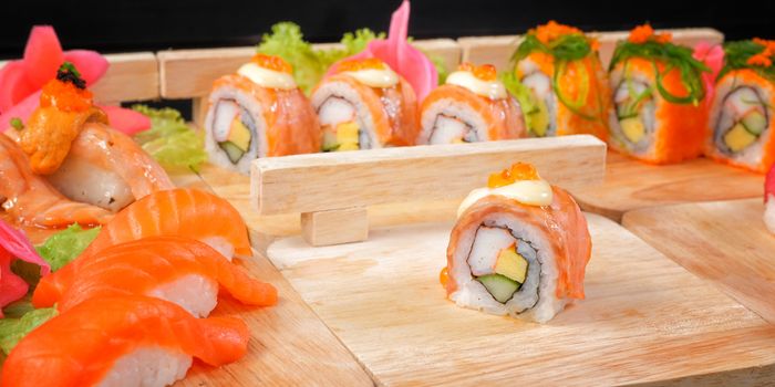 Japanese Cuisine - Sushi Roll on wood plate in black background
