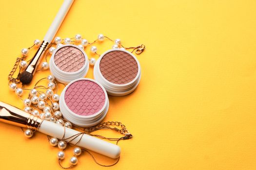 Eyeshadows and makeup brushes on a yellow background top view professional cosmetics. High quality photo