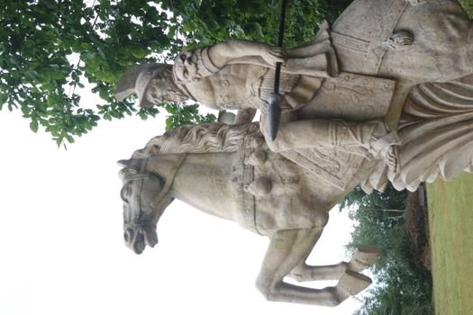 Statue made of white stone marble of an ancient famous soldier riding on the horse- White marble statue of an ancient man holding a scroll and riding a horse