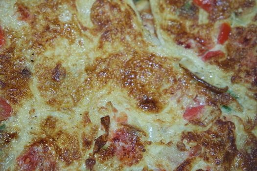 Close-up view with selective focus of egg omelet with peppers and spices sprinkled