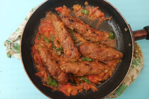 Closeup view of delicious spicy home made fried kebab with green mint leaves and green pepper sprinkled on it