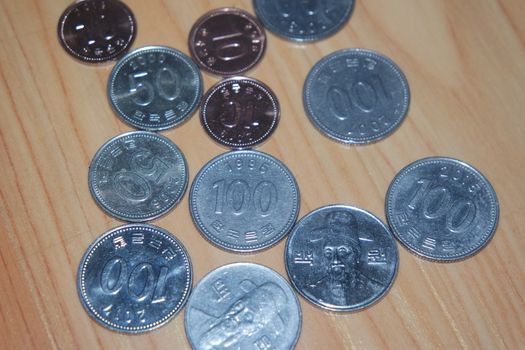 Silver shining Korean won coin scattered over a wooden floor.