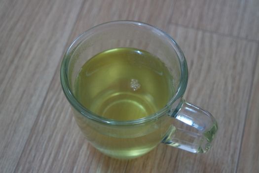 Glass cup having brewed fragrant green tea or qehwa or qahwa on the wooden floor. It is served with sugar or honey and nuts