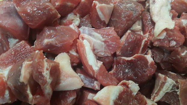 Close up view of fresh finely chopped meat cubes. Red meat small steaks with whitish meat fat.