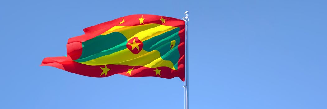 3D rendering of the national flag of Grenada waving in the wind against a blue sky