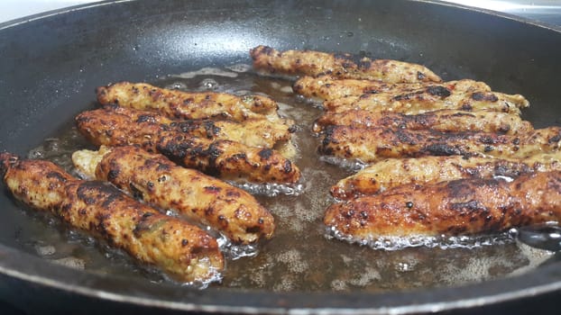 Delicious spicy fried long kebab served in black hot plate with boiling oil