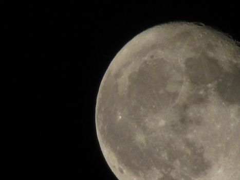 Earth's Moon Glowing On Black Background. The Moon close-up on a black night sky shot through a telephoto camera.