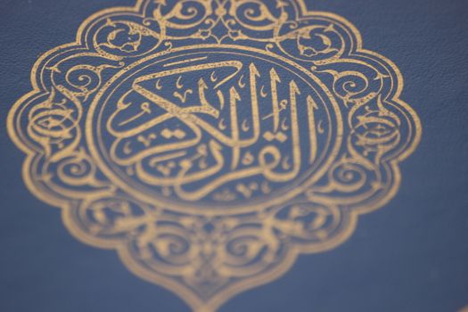 Closeup shot of Islamic Book Quran with golden arabic calligraphy that means Al-Quran, the Holy Quran