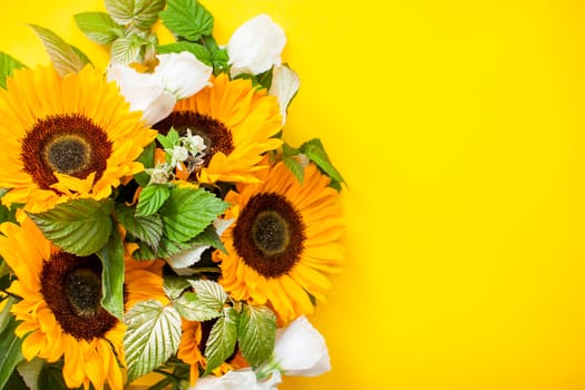 Bright juicy bouquet of sunflowers and white eustomas on a bright yellow background. Layout. Flat lay.