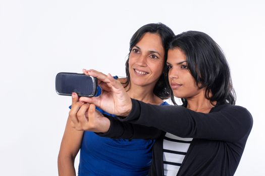 A woman and a girl taking a selfie with a cell phone. They both have black hair