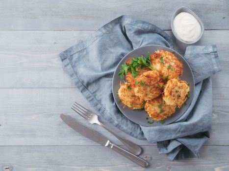 Close up view of potato pancakes. Potato flapjack on gray plate over gray wooden table, with fresh parsley and sour cream. Copy space for text. Top view or flat-lay.