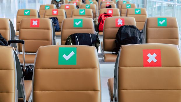 Social distancing, Rows of empty chairs in an airport's departure area marked with symbols regarding social distancing protocol to prevent the spreading of novel corona virus, COVID-19 in Thailand