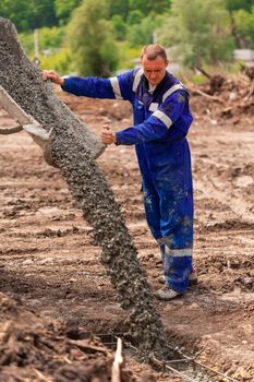 Construction worker laying cement or concrete into the foundation formwork. Building house foundation