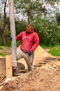 Construction worker laying cement or concrete into the foundation formwork with automatic pump. Building house foundation