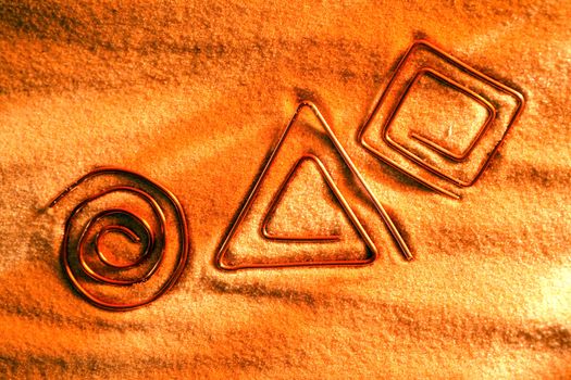 Abstract symbols made from copper wire on sand surface