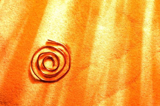 Abstract spiral symbol made from copper wire on sand surface