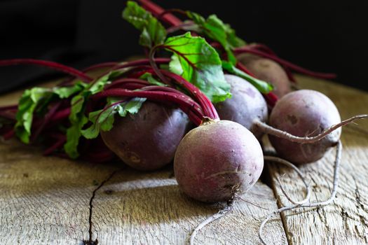 Bunch of fresh, spring, organic beetroot on old wooden background. Horisontal view. Rustic, dramatic, organic kitchen. Ingredients, menu. Healthy life, diet concept