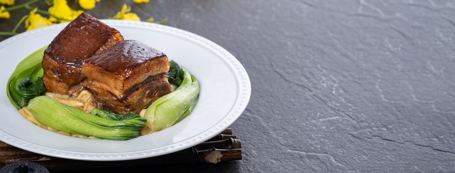 Dong Po Rou (Dongpo pork meat) in a beautiful plate with green vegetable, traditional festive food for Chinese new year cuisine meal, close up.