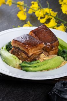 Dong Po Rou (Dongpo pork meat) in a beautiful plate with green vegetable, traditional festive food for Chinese new year cuisine meal, close up.