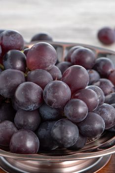 Delicious bunch of grapes fruit on a plate over wooden table background.