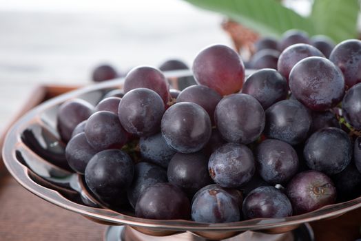 Delicious bunch of grapes fruit on a plate over wooden table background.