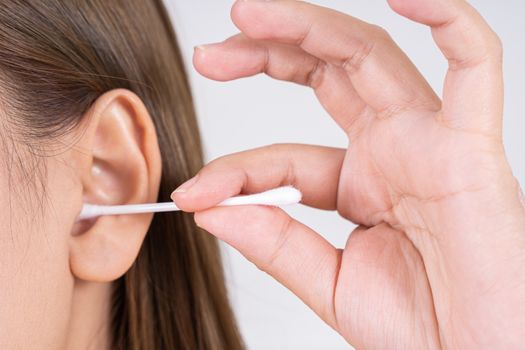 woman cleaning her ear with a cotton swab. A woman suffered an infection after using the sticks incorrectly.