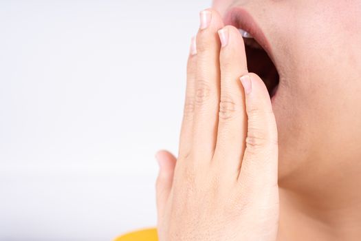 Asian woman are yawning covering open mouth with hand after she wake up. Healthcare medical or daily life concept.