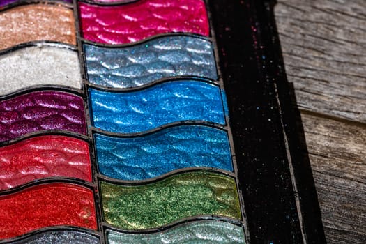 Make up eyeshadow palette close up isolated on wooden background with copy space.