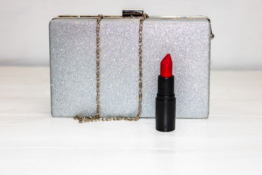 Glittery silver clutch bag with red lipstick isolated on white background with copy space.