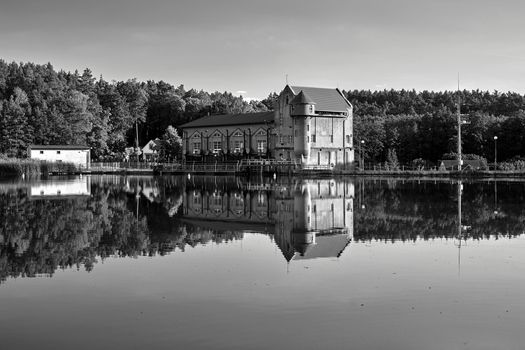 the reservoir and the building of a historic hydroelectric power plant in Bledzew in Poland, black and white