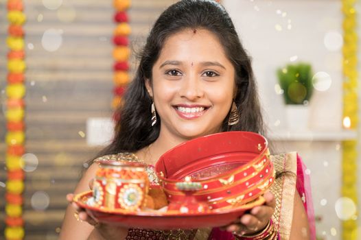 Close up POV shot of Indian Married woman in traditional dress holding Karva Chauth Thali or plate and looking into camera during Indian religious karwa chauth festival