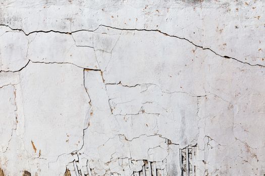 poor wattle and daub cracked stucco wall with white plaster.
