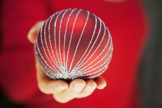 Hand holding red Christmas decoration