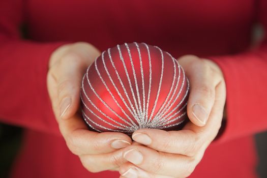 Hands holding red Christmas decoration