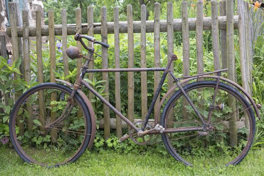 Old rusty bicycle leaning against a wooden fence