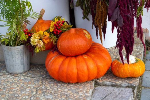 Orange pumpkins of various sizes lie on the porch of the house.The Concept Of Halloween.