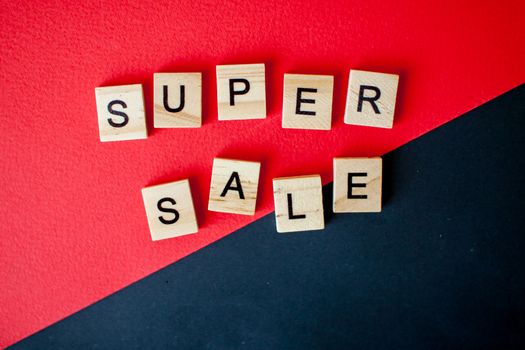 The inscription super sale from wooden blocks on a black and red background