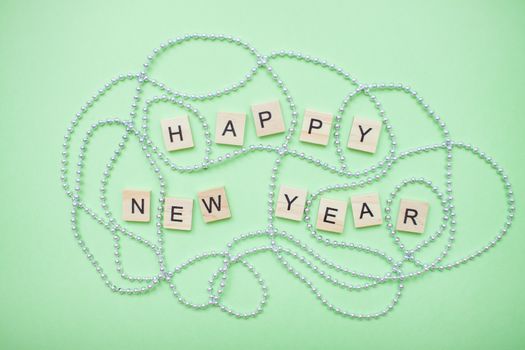 inscription happy new year in a new year frame of silver beads on a green background