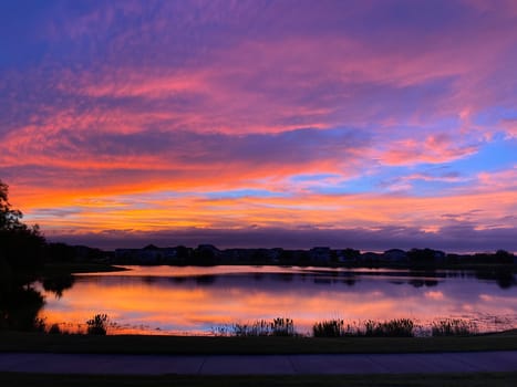 Beautiful pink, orange and blue sunset reflecting on a lake in a suburban neighborhood.