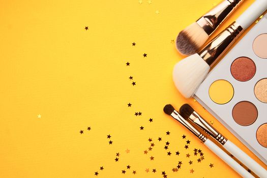 Eyeshadows and brushes for makeup glitter yellow background professional cosmetics. High quality photo