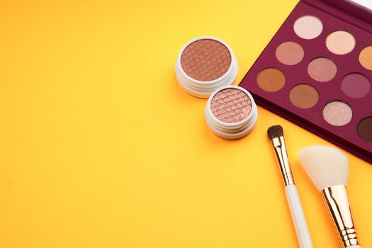 Professional eyeshadows and makeup brushes on a yellow background make-up decoration. High quality photo