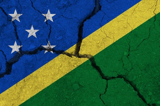 Solomon Islands flag on the cracked earth. National flag of Solomon Islands. Earthquake or drought concept