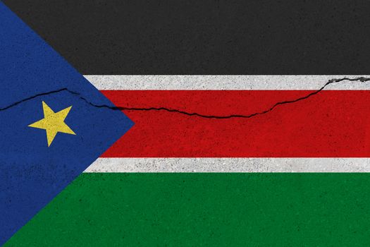 South Sudan flag on concrete wall with crack. Patriotic grunge background. National flag of South Sudan