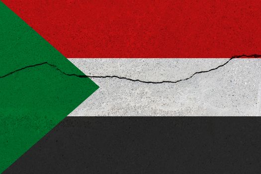 Sudan flag on concrete wall with crack. Patriotic grunge background. National flag of Sudan